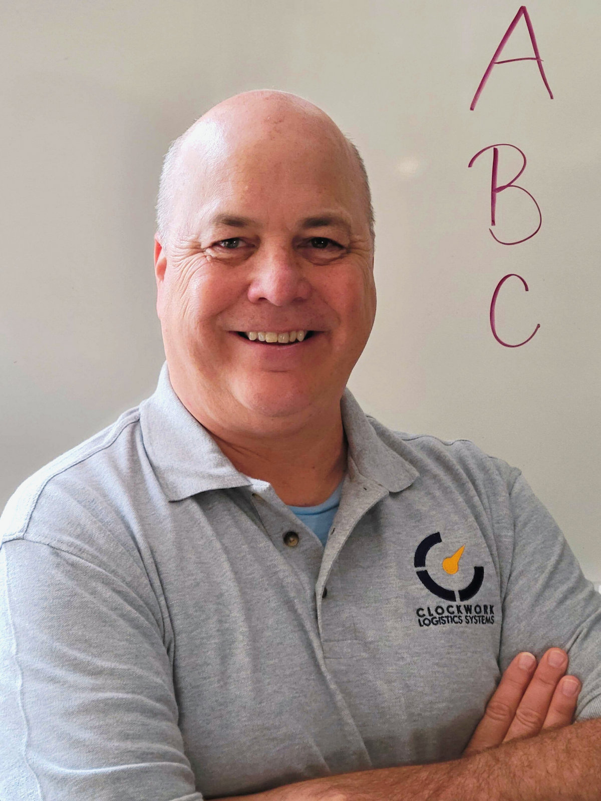 Rob Haney standing with arms crossed in front of a whiteboard with ABC written on it.